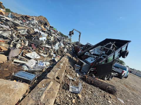 Xenya's LLC dump trailer unloading scrap and appliances at the recycling yard
